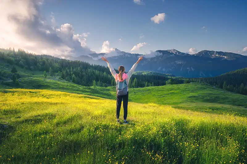 happy healthy ultrasound patient standing on hill with arms up in celebration