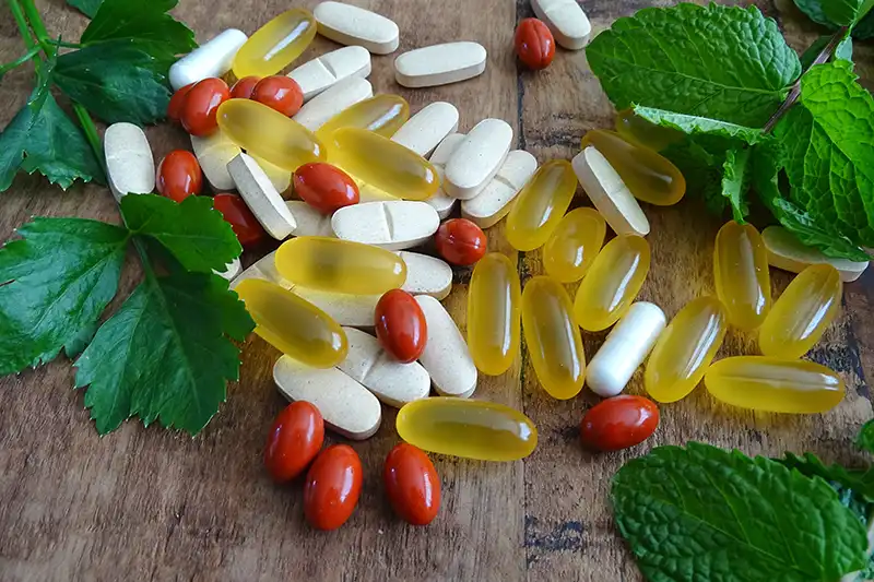 close up of herbal supplements and prescription pills mixed together on table